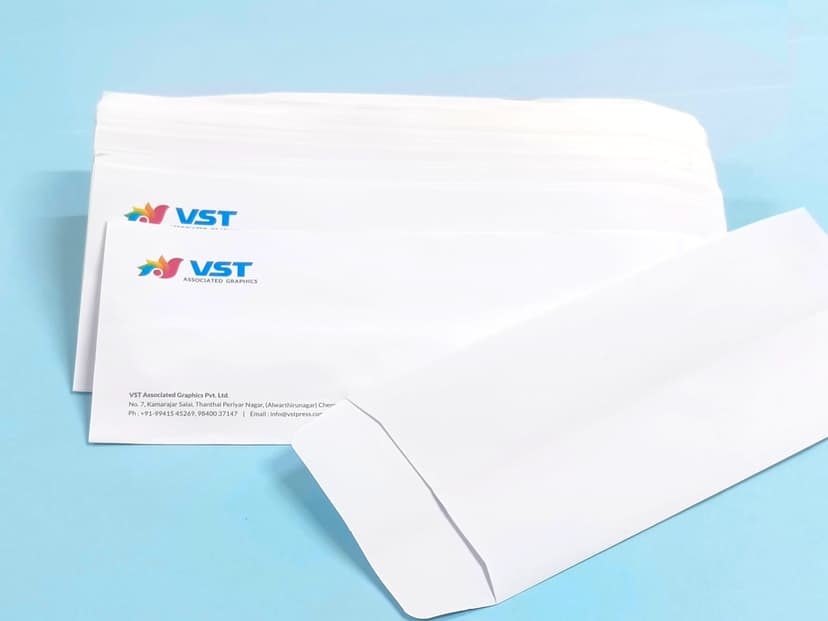 Stacked white office envelopes with VST Associated Graphics logo and address.