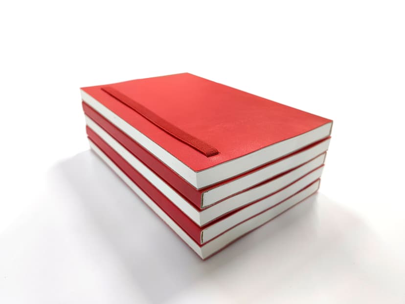 Stacked red diaries highlighting the elastic band and spine quality.